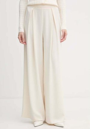 Pantaloni a vita alta e gamba larga color crema con pieghe anteriori, indossati con scarpe crema abbinate con punta a punta e una maglia a maniche lunghe con texture.