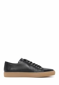 Sneaker in pelle nera con profilo basso, punta rotonda e lacci neri. Presenta una tomaia testurizzata e una suola in gomma beige per un contrasto.