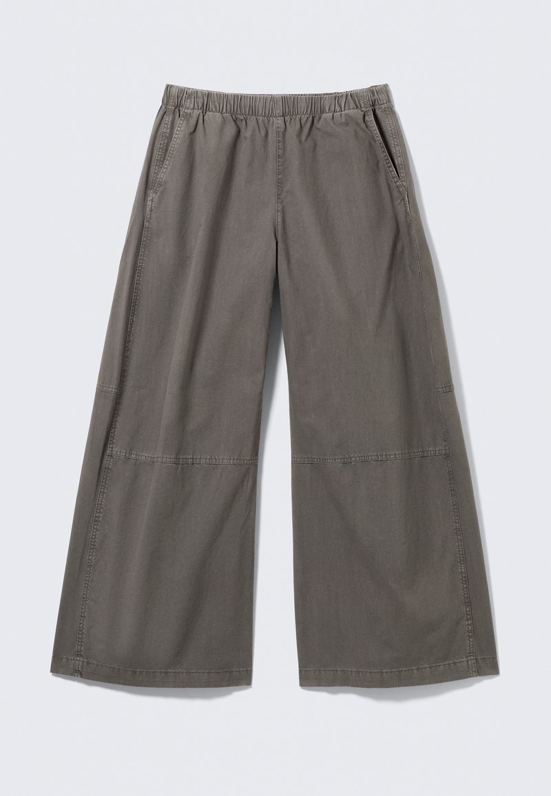 Pantalon à jambes larges de couleur grise douce, en tissu lisse, doté d'une ceinture élastique et de poches latérales, avec des coutures décoratives.