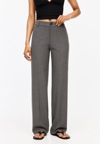 Pantalons large gris en tissu texturé, dotés d'un bouton à l'avant et d'une taille normale. Drapeau fluide jusqu'aux chevilles.