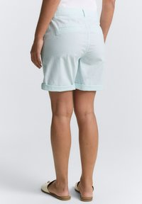 Shorts en coton bleu clair avec des ourlets retroussés, dotés de deux poches arrière et d'une taille plate. Texture lisse et coupe décontractée.