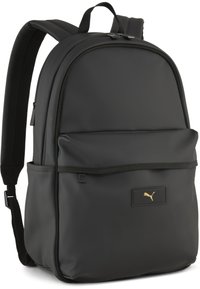 Rucsac negru cu un finisaj mat, neted. Include bretele căptușite, un buzunar frontal și un logo aurie Puma pe un patch rectangular.