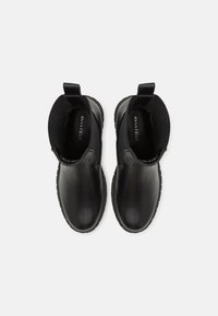 Bottines noires avec une finition en cuir lisse, des panneaux latéraux en élasthanne et des tirants, dotées de semelles en caoutchouc texturé pour une meilleure adhérence et durabilité.