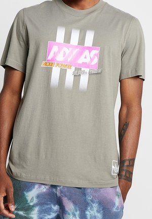 Olivegrünes Baumwoll-T-Shirt mit einem mehrfarbigen Adidas-Graphic, einschließlich pinker und oranger Schrift, mit weißen vertikalen Streifen.