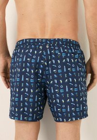 Marinefarbene Badeshorts mit elastischem Bund; mit einem Muster aus blauen und gelben, sommerlichen Symbolen wie Palmen, Surfbrettern und Cocktails.