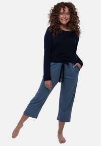 Mörkblå långärmad topp i kombination med ljusblå cropped byxor med dragsko i midjan och sidofickor. Mjuk tyg med slät yta.