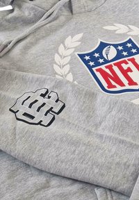 Gray sweatshirt with NFL logo featuring a football, laurel design, and black graphic on sleeve. Soft fabric with a textured appearance.