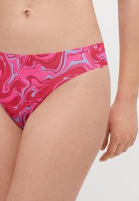 Rosa svømmebukser med et virvlende marmormønster i nyanser av rosa og blått, med et logomerke på midjebåndet. Mykt, elastisk stoff.