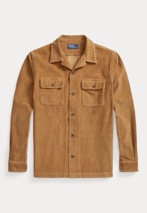 Chemise en velours côtelé marron clair à boutons, manches longues, deux poches poitrine boutonnées et col plié.