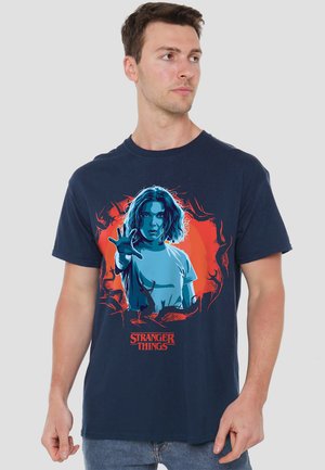 Navy cotton t-shirt featuring a graphic of a girl with wavy hair, outstretched hand, and “Stranger Things” text in bold red beneath.