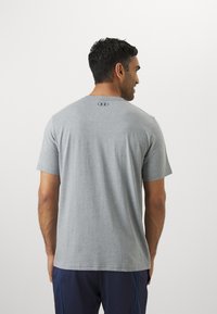 Grå kortærmet t-shirt lavet af en bomuldsblanding, med rund halsudskæring og diskret logo på ryggen.