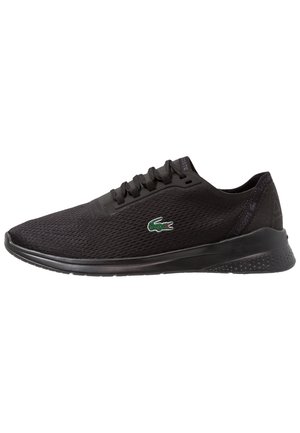 Czarny sportowy sneaker z siateczkową cholewką, czarną podeszwą, sznurówkami i zielonym logo krokodyla Lacoste z boku.