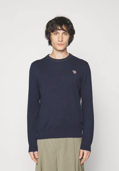 Pull bleu marine en tissu doux, avec un col rond agrémenté d'accents verts et un petit logo d'éléphant brodé sur la poitrine.