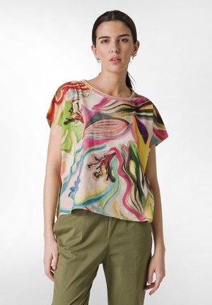 Multicolored short-sleeve top with floral patterns, lightweight fabric, and a loose fit. Paired with light green, relaxed-fit pants.