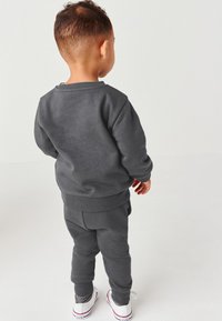 Dunkelgrauer Pullover und passende Jogginghose, mit gerippten Bündchen und Bund. Schlichte Gestaltung ohne sichtbare Muster oder Akzente.