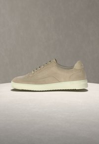 Μπεζ σουέντ αθλητικό παπούτσι με λευκή ραβδωτή σόλα και σχέδιο με κορδόνια, εμφανίζεται σε φόντο και επιφάνεια σε ουδέτερους τόνους.