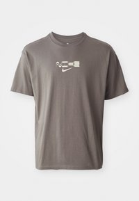 Brun kortærmet t-shirt med et lysfarvet "Nike" logo trykt på forsiden, med en afslappet og løs pasform.