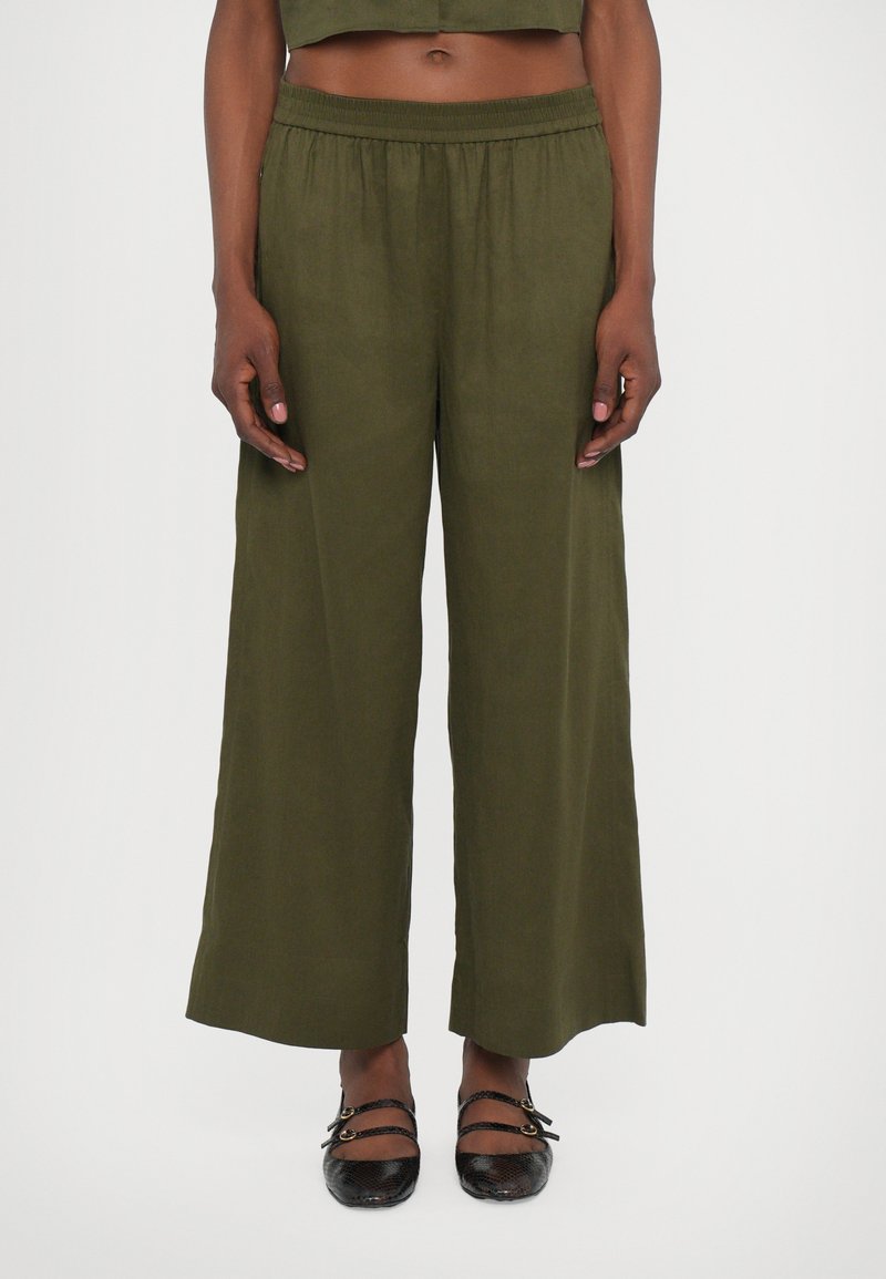 Pantalons larges en vert olive, dotés d'une taille élastique confortable et d'un tissu léger et texturé. Pas de motifs ou de détails marquants.