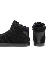 Melni augstie sporta apavi, kas izgatavoti no zamšādas ar gludas ādas akcentiem, ar auklu aizdari un sānu rāvējslēdzēju. Plakans melns gumijas zole.