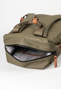 Olivgrüner Rucksack mit gepolsterten Trägern, Lederakzenten und teilweise geöffnetem Hauptfach, das eine gemusterte Innenauskleidung zeigt.