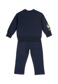 Mörkblå sweatshirt och byxor set i bomull. Rund halsringning, ribbade ärmslut, med textdetalj på ärmen och en ficka på baksidan.