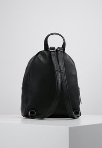 Czarny skórzany plecak o zaokrąglonym kształcie, z górnym uchwytem, regulowanymi paskami i srebrnymi elementami metalowymi. Gładka faktura z zamkiem błyskawicznym.