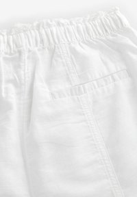 Bijeli materijal s teksturiranim završetkom koji ima elastičnu waistband i jednu stražnju džep s prošivenim rubom.