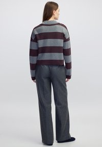 Gestreepte trui in bordeauxrood en grijs, cropped fit met een kraag. Gecombineerd met grijze wijde broek, gemaakt van een textiel met structuur.