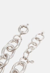 Stříbrné náušnice z řetízku s propojenými oválnými a kulatými články, leštěný povrch a decentní značení na malém štítku.