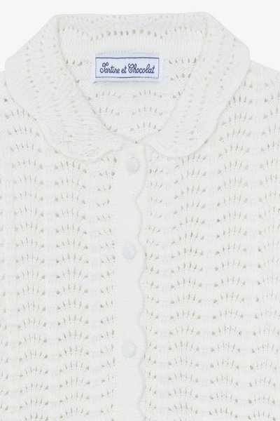 Λευκό πλεκτό ζακέτα με κυματιστό γιακά, με υφασμένο μοτίβο και κούμπωμα με κουμπιά. Η ετικέτα γράφει "Tartine et Chocolat."