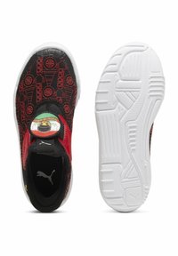 Des baskets noires et rouges pour enfants, à enfiler, avec un design de dessin animé sur le dessus et des semelles en caoutchouc texturé blanc, une chaussure vue de dessus, l'autre de dessous.