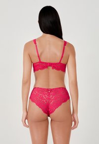 Set di lingerie in pizzo rosa con reggiseno a spalline regolabili e chiusura a gancio, e slip a vita alta abbinati con bordi smerlati.
