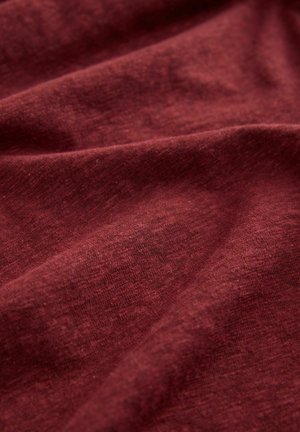 Tissu en coton bordeaux avec une finition texturée, présentant de douces ondulations et un aspect légèrement chiné, indiquant flexibilité et confort.