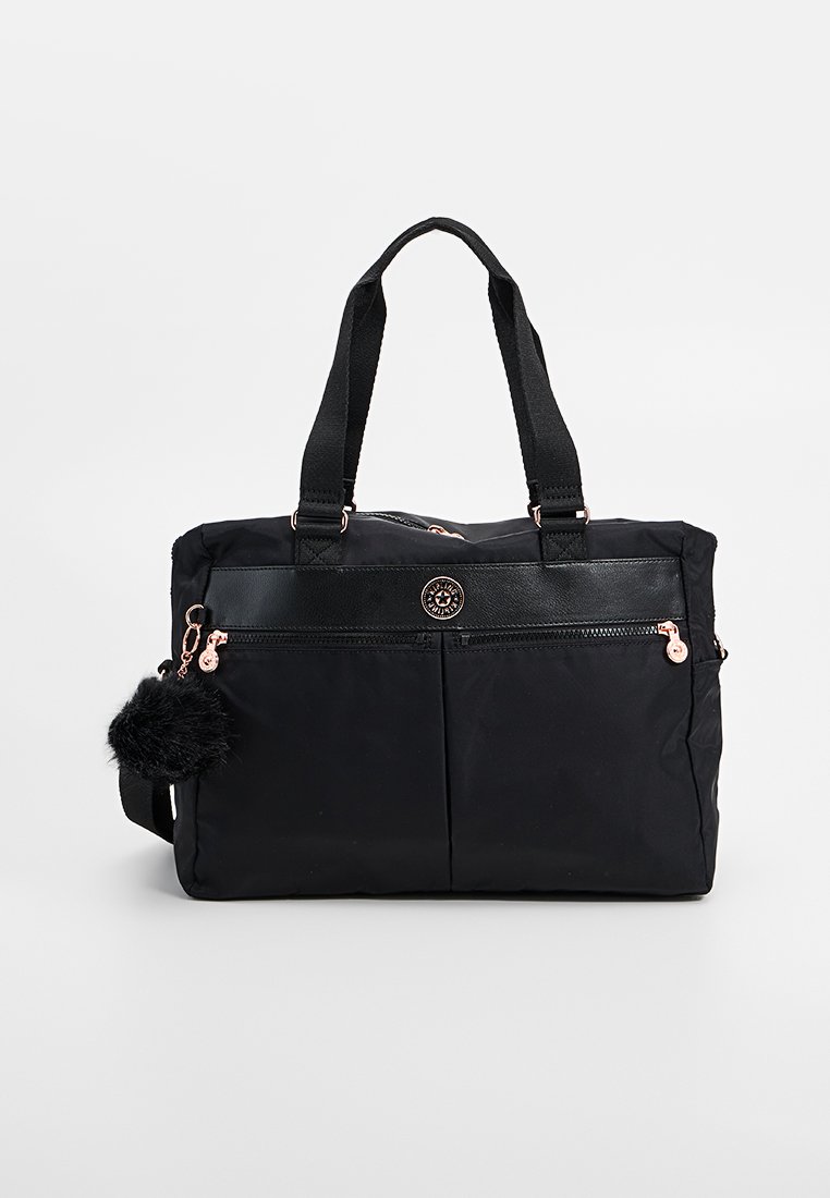 Zwarte nylon tas met dubbele handvatten, voorzien van een voorzak met ritssluiting, lederen accenten en een afneembare fluffy pompon sleutelhanger.