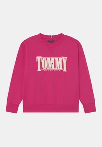 Sudadera fucsia con un gran logo bordado de "TOMMY HILFIGER" en color crema. Cuello redondo, puños y dobladillo acanalados, con un acento de logo en la manga.