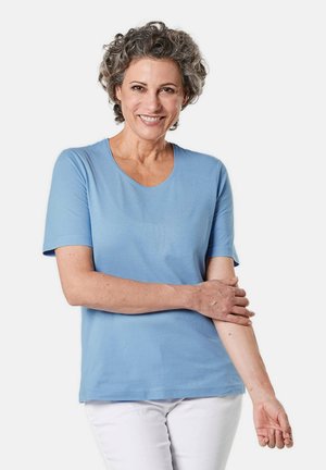 Helles blaues T-Shirt mit kurzen Ärmeln aus glattem Stoff und rundem Ausschnitt, getragen mit weißen Hosen. Keine sichtbaren Muster oder Akzente.
