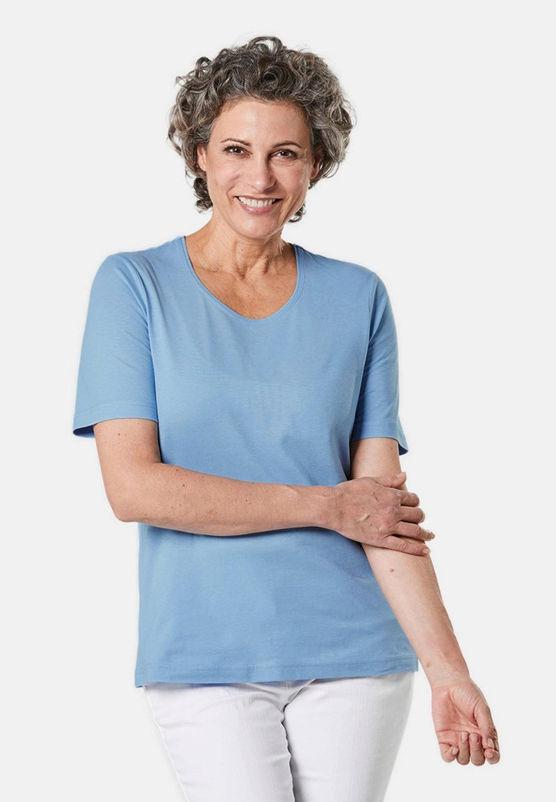 Lichtblauw T-shirt met korte mouwen in een soepele stof en een ronde halslijn, gedragen met witte broeken. Geen zichtbare patronen of accenten.