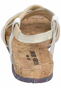 Sandalo in sughero beige con cinturini accentuati in argento e plantare texturizzato. Presenta una suola multicolore con una leggera curvatura. Vista da dietro.