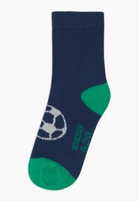 Chaussette marine avec des accents verts au niveau des orteils et du talon. Présente un motif de ballon de soccer blanc et un haut côtelé pour un bon maintien. Fabriquée en matériau textile doux.