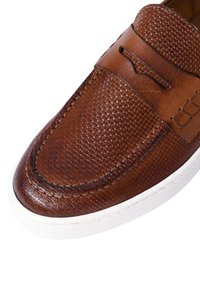 Scarpa slip-on in pelle marrone con texture intrecciata, punta arrotondata e suola in gomma bianca. Presenta dettagli in pelle liscia e cuciture.