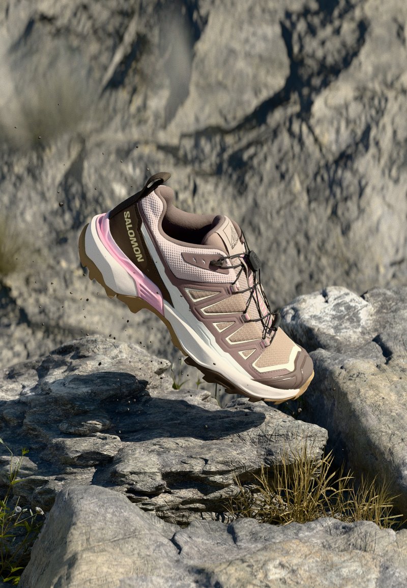 Letvægts trail løbesko i beige og pink, med mesh-overdel, polstret sål og struktureret ydersål for greb, der har et strømlinet design.