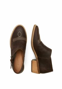 Botas de cuero marrón hasta el tobillo con un pequeño tacón de madera. Incluyen costuras blancas en contraste y un diseño recortado en los laterales.