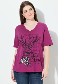 T-shirt violet à manches courtes avec col en V, présentant un motif de cerf et un design floral imprimé en noir et blanc avec des accents de texte.
