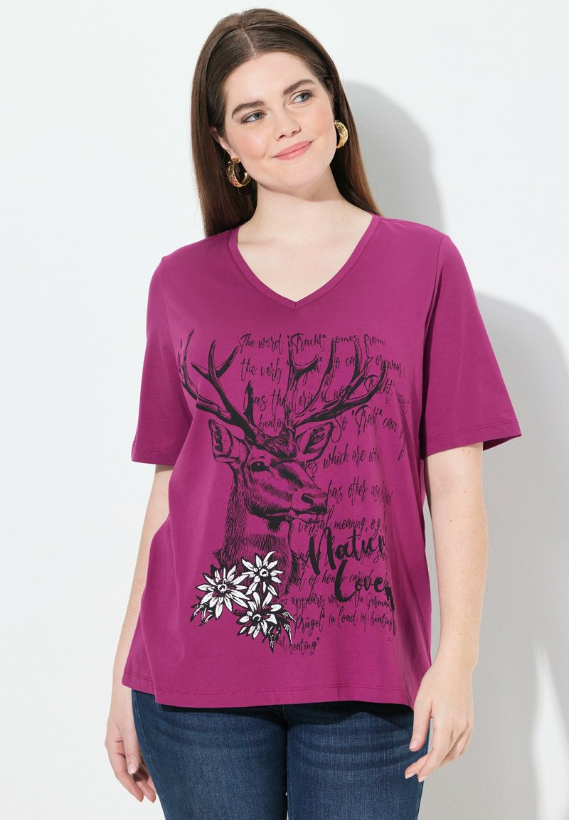T-shirt violet à manches courtes avec col en V, présentant un motif de cerf et un design floral imprimé en noir et blanc avec des accents de texte.