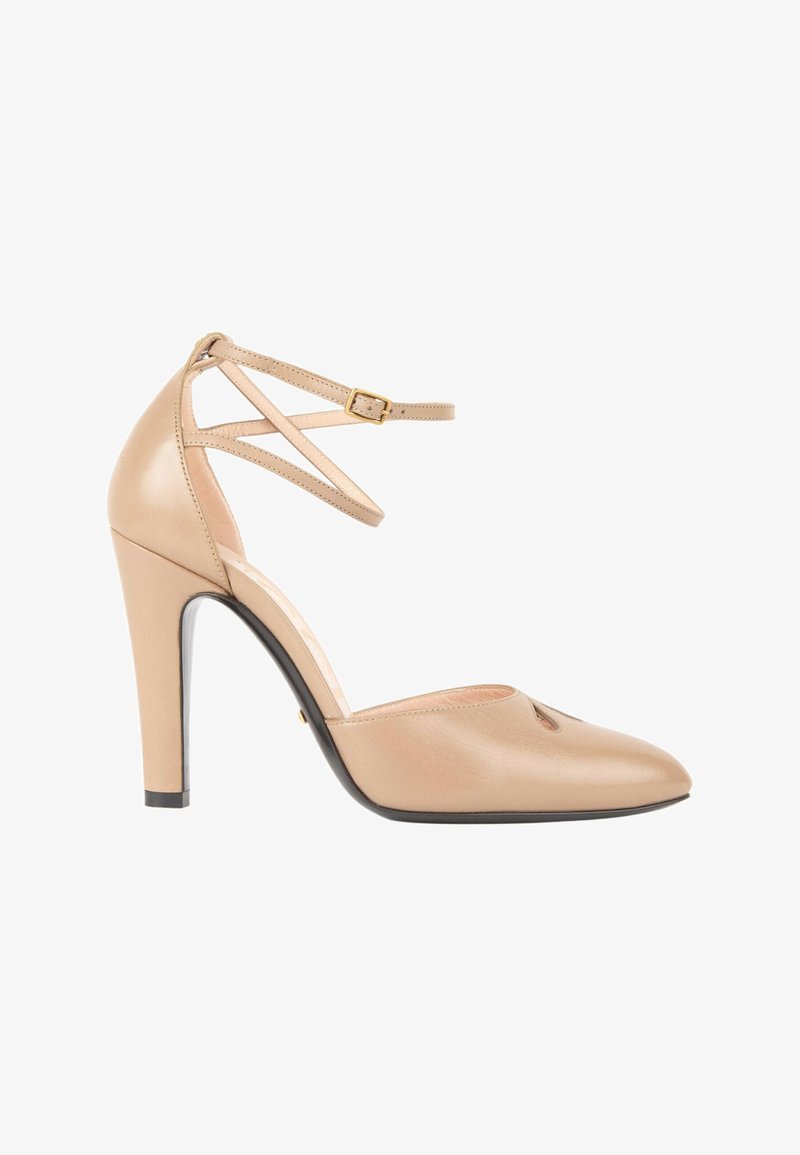 Chaussure à talons hauts beige à bout pointu, en cuir, avec fines brides de cheville et boucle dorée, vue de profil.