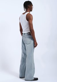 Jasnoniebieskie dżinsy o szerokich nogawkach, wykonane z denimu, z klasycznym pięciopocketowym wzorem i czarną metką w talii.