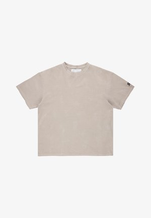 Beżowy bawełniany t-shirt o luźnym kroju, z okrągłym dekoltem, krótkimi rękawami i subtelną wzorzystą fakturą. Logo "S" na lewym rękawie.