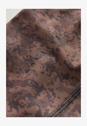 Brauner Stoff mit einem marmorierten Muster, das das Wort "ACTIVE" in schwarzer Schrift und eine sichtbare Nahtdetail aufweist.