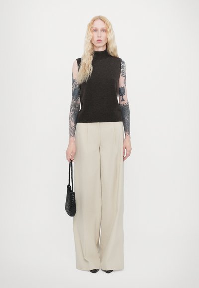 Dark brown sleeveless knit top, high neck, beige wide-leg trousers, black handbag, and black pointed shoes. Smooth texture, minimalist design.