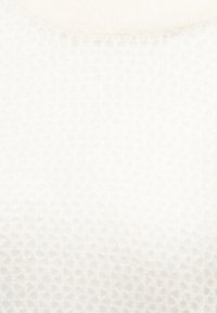 Une texture alvéolée blanche douce crée un motif géométrique subtil avec une sensation de légèreté et d'aération.